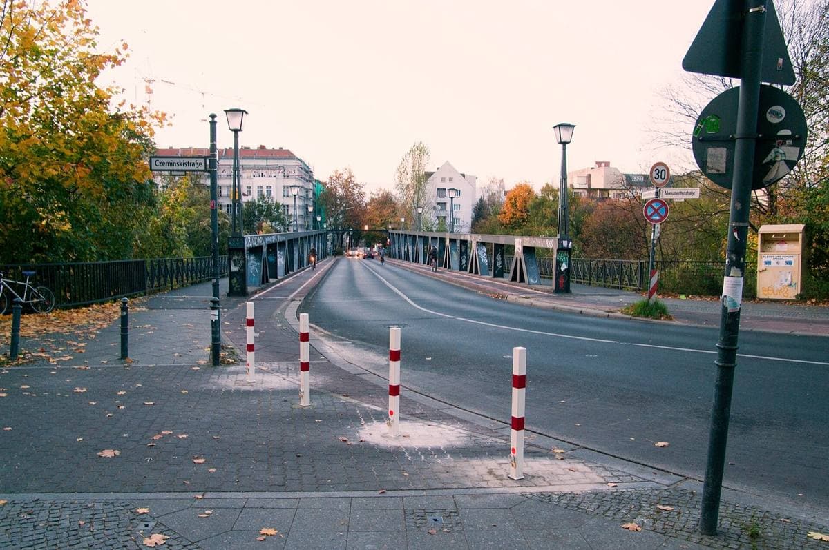 A steel truss bridge with a curving road and autumn trees