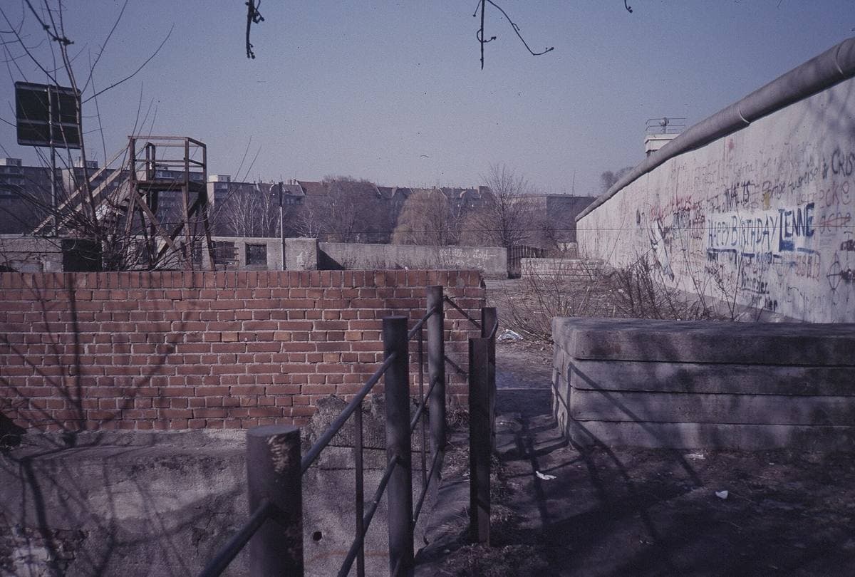 The Berlin Wall closing off the end of a bridge, with a watchtower beyond