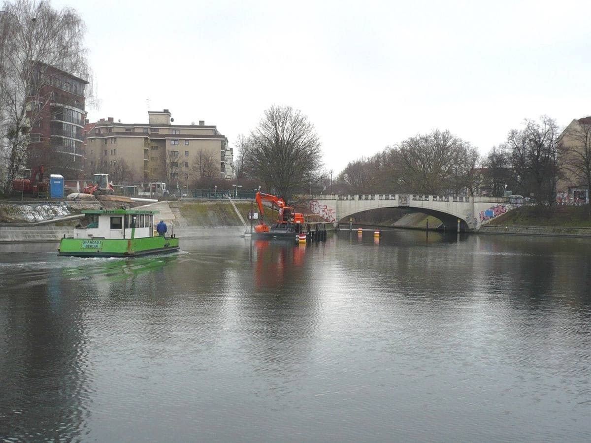 A low arched bridge over a wide canal with bare trees