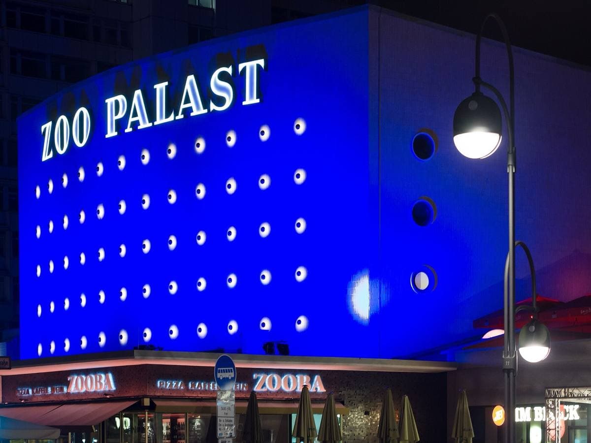 A cinema front glowing blue at night with the name ZOO PALAST