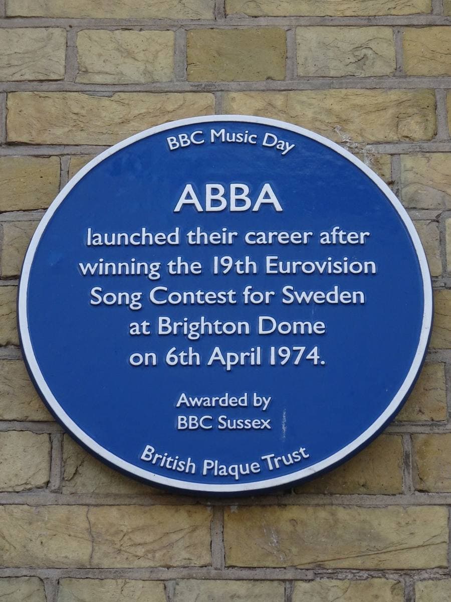 A round blue plaque on a yellow brick wall