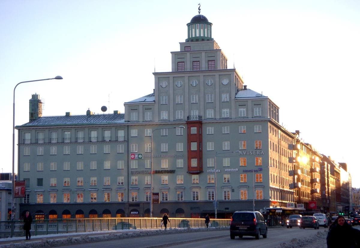 A tall pale-green 1930s block with a stepped tower, seen from a bridge in winter light