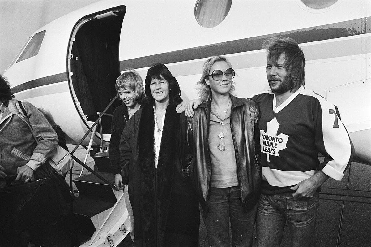 The four members of ABBA standing beside the steps of a small white jet