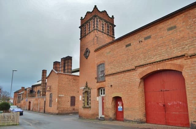 A red-brick foundry with a tower and tall red doors