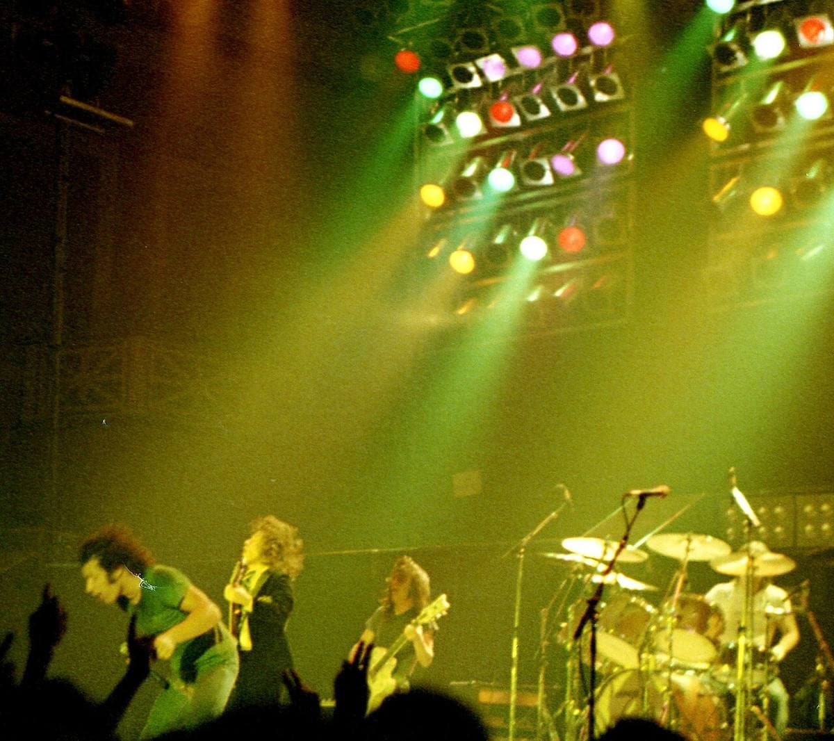 Brian Johnson, Angus Young and Malcolm Young on stage under white lights in 1980