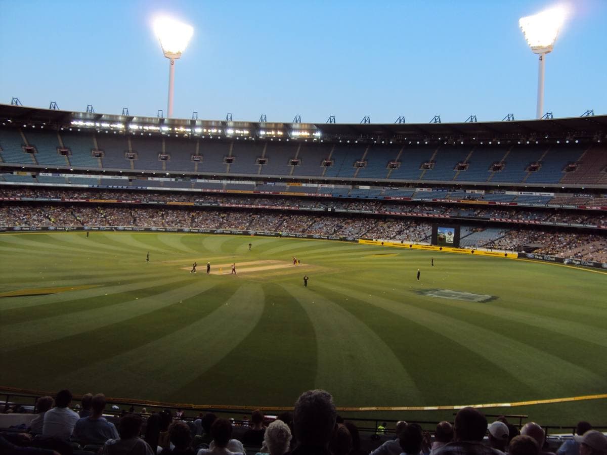 A huge oval stadium bowl full of people under floodlights