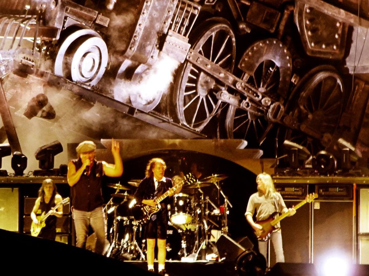 The band on a lit stage under a giant model locomotive