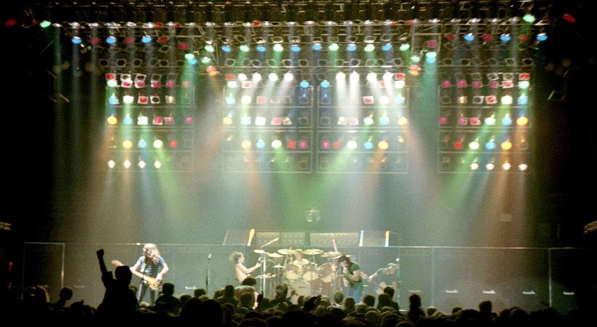 AC/DC on a dark stage under a full rig of white lights in 1980