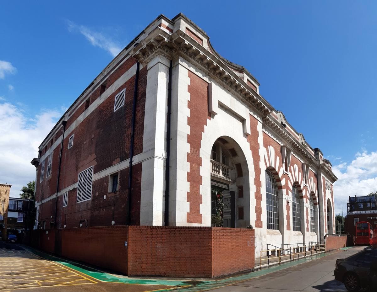 A red-brick and white-stone Edwardian power station with tall arched windows on a street corner