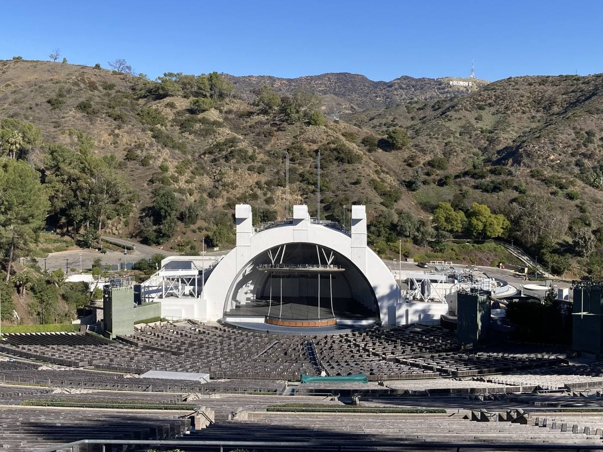 The white arched shell of the Hollywood Bowl in front of hills and the Hollywood sign