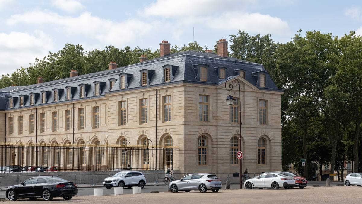 A long pale stone wing of a seventeenth-century stable building with tall arched windows