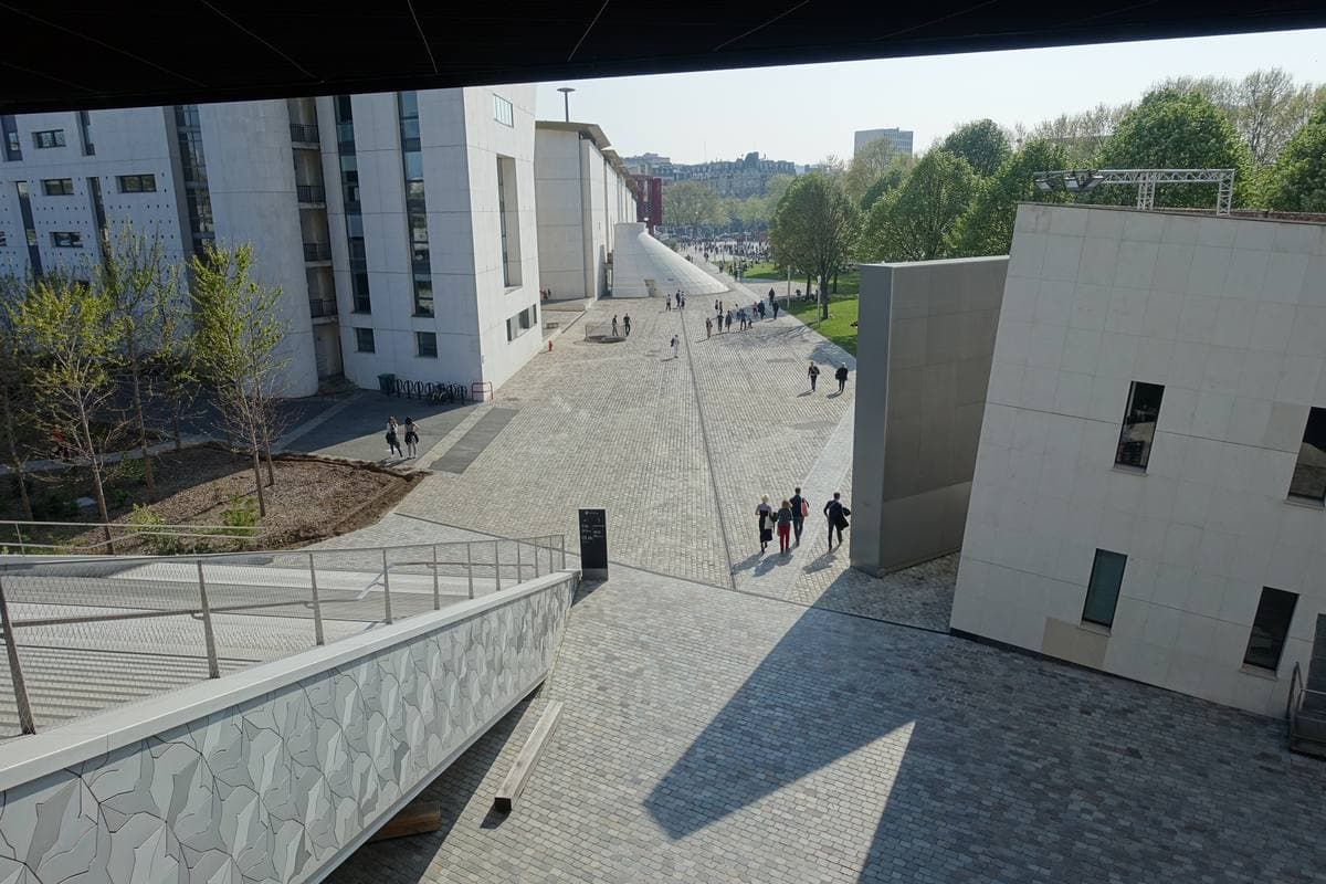 The silver, bird-scale cladding of the Philharmonie de Paris rising over a lawn