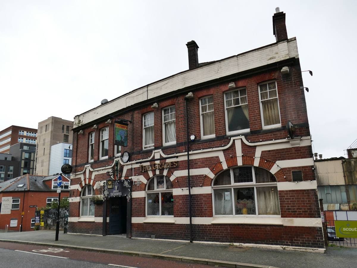 A red-brick and cream corner pub with arched windows on a city-centre lane