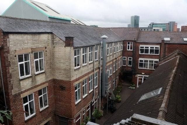 Brick and stone works buildings round a yard, the city’s towers in the distance