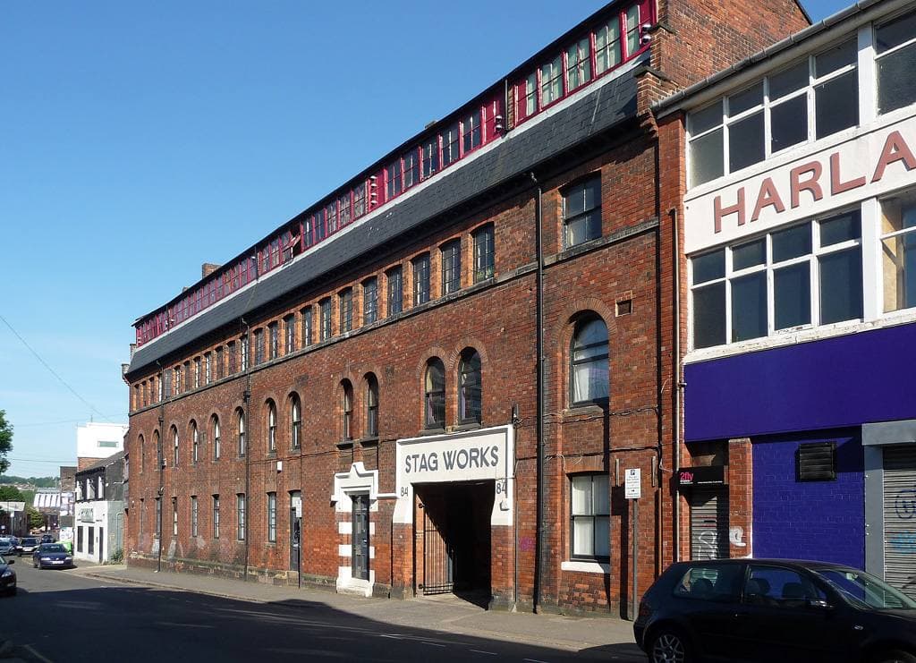 A long red-brick works on a street corner with an arched entrance marked STAG WORKS