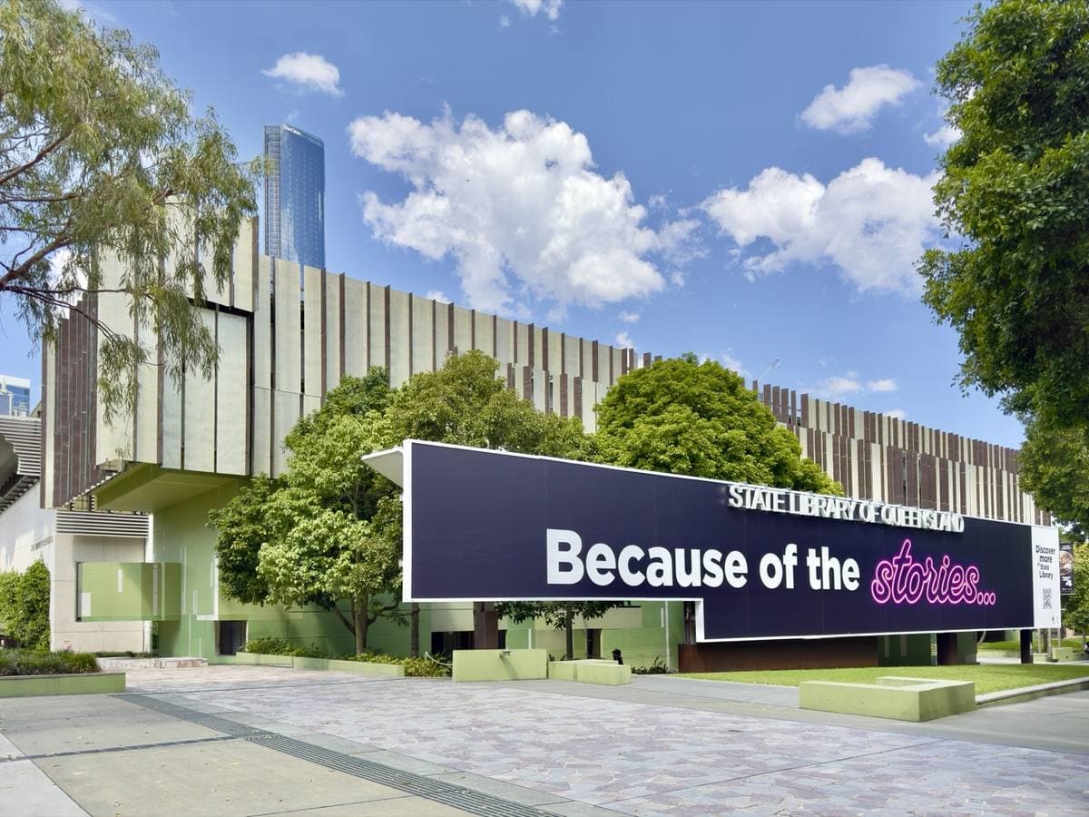 A long low modern library building with fins on its upper floor, behind a paved forecourt