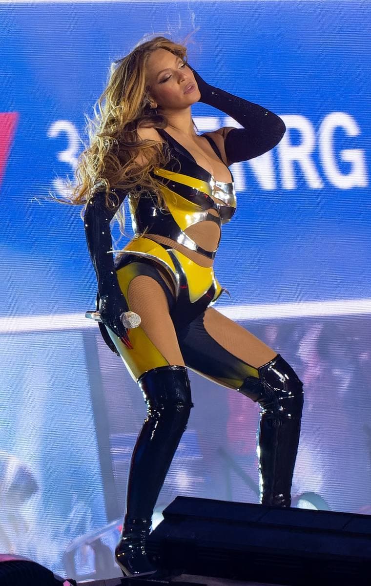Beyoncé on stage in a yellow and black bodysuit and long black gloves and boots