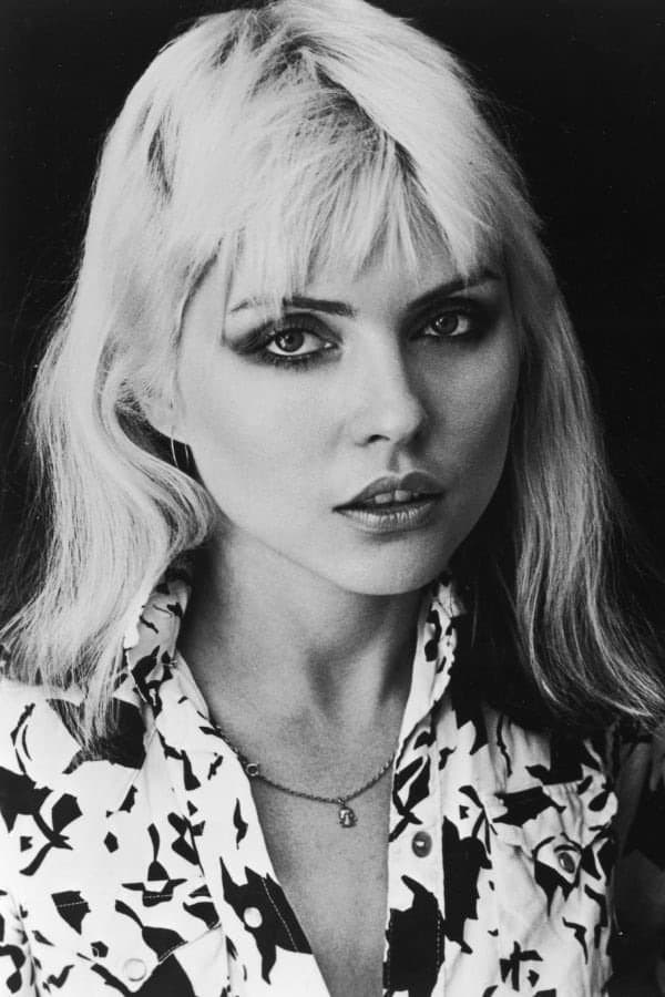 Debbie Harry in black and white, blonde hair falling over one eye, in a patterned shirt