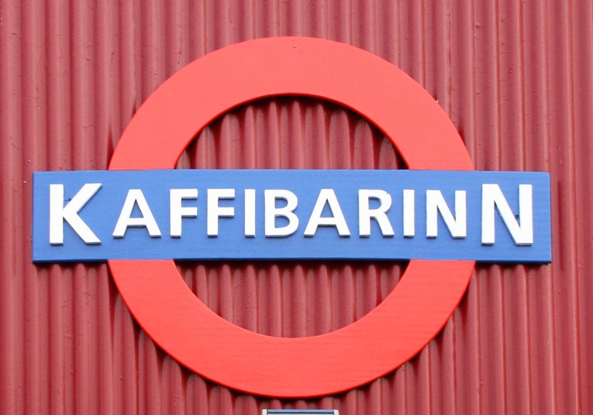 The bar's name in white capitals on a blue bar across a red ring, fixed to red corrugated-iron walls