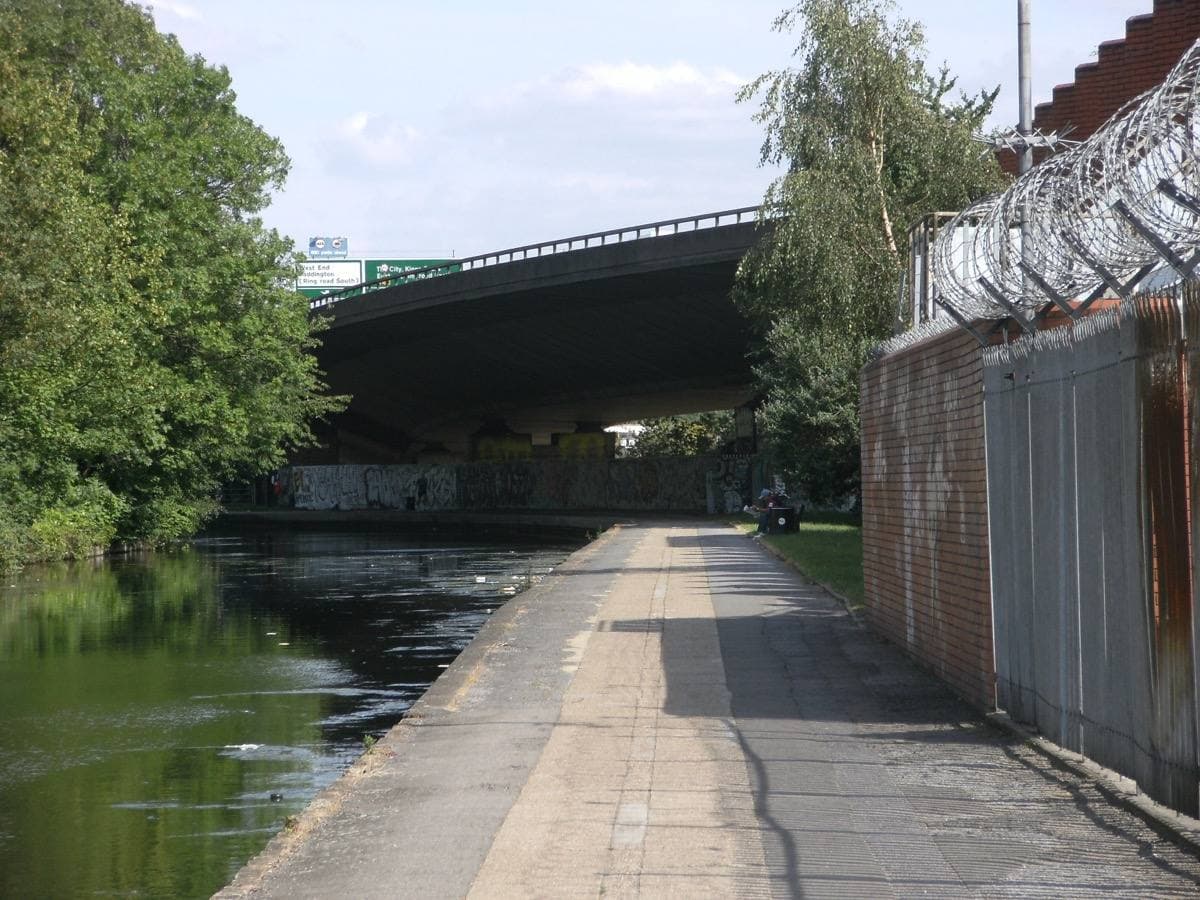 The concrete deck of the Westway flyover on its pillars above the canal towpath in west London