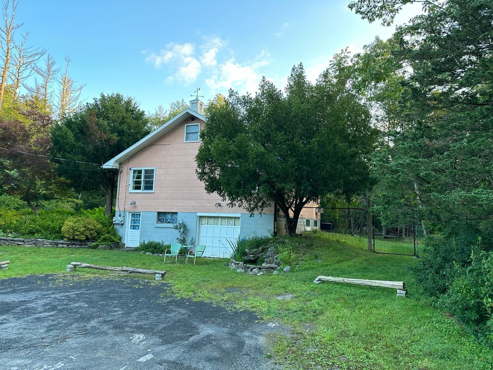 A pink ranch house in a clearing in the woods