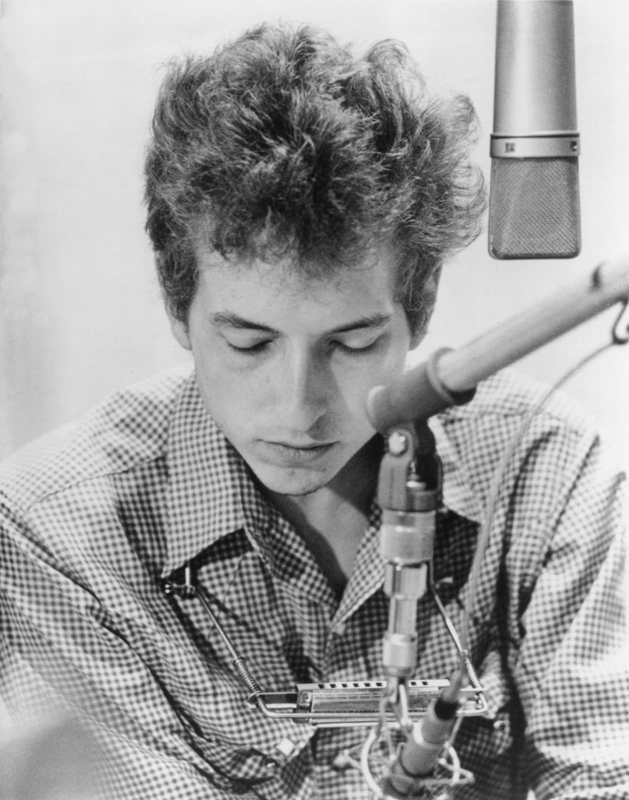 Bob Dylan in a recording studio, looking down, in a work shirt