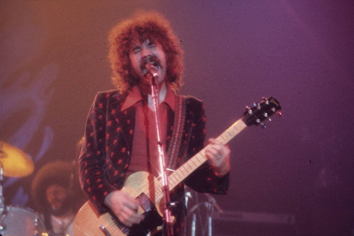 Brad Delp singing into a microphone on stage in 2006