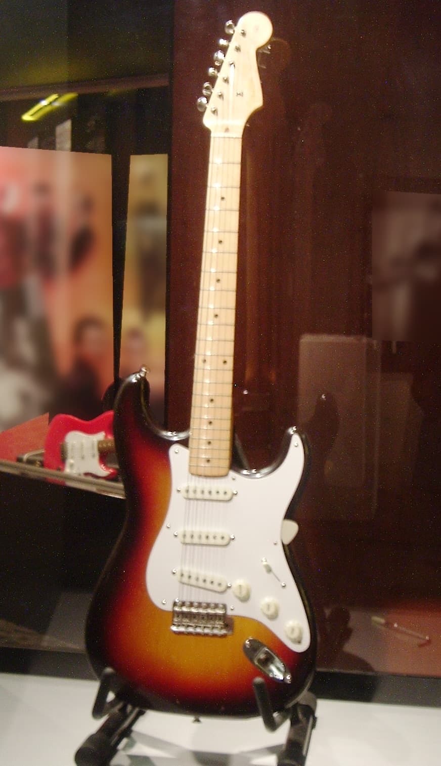 A sunburst Fender Stratocaster guitar in a display case