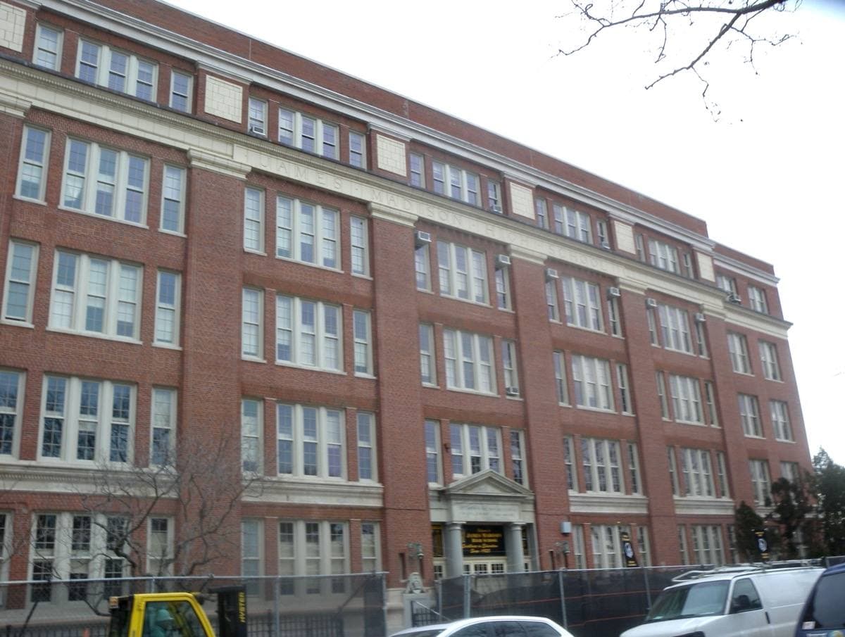 A long red-brick school with a white cupola behind bare trees