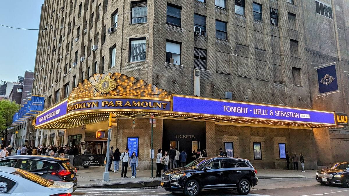 A lit theatre marquee reading Brooklyn Paramount under a tall brick building