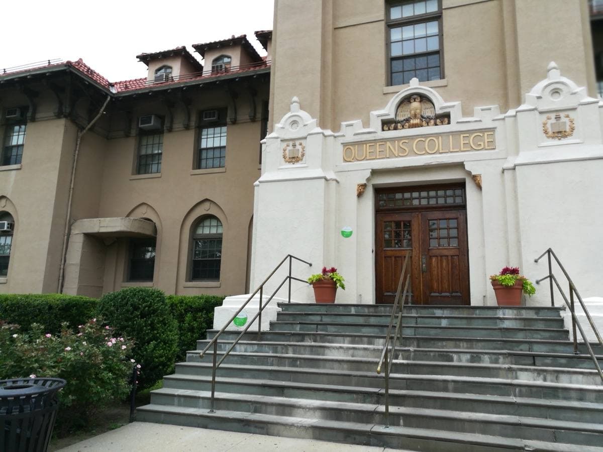 White stucco college building with a red tiled roof and wide steps
