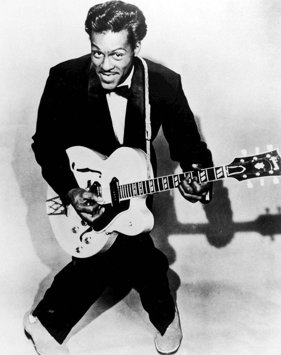 Chuck Berry smiling, holding an electric guitar, in a studio portrait