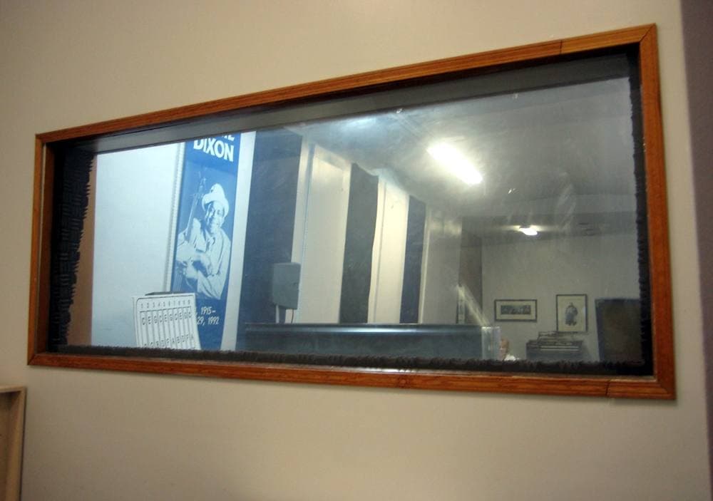 A recording control booth with a window to the studio