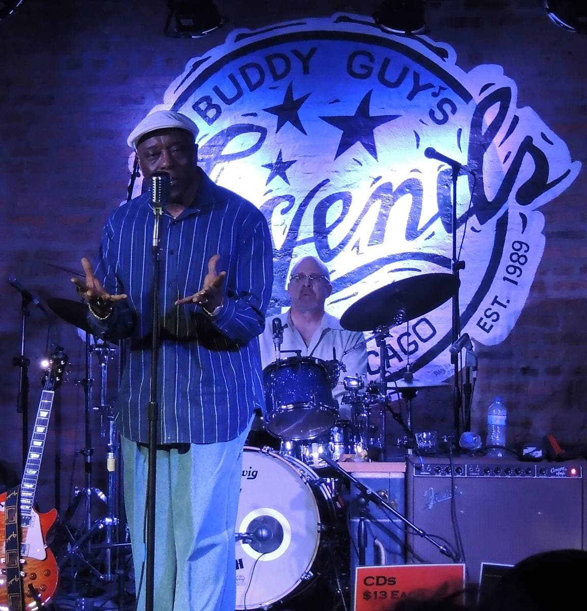Buddy Guy playing a polka-dot guitar on a club stage
