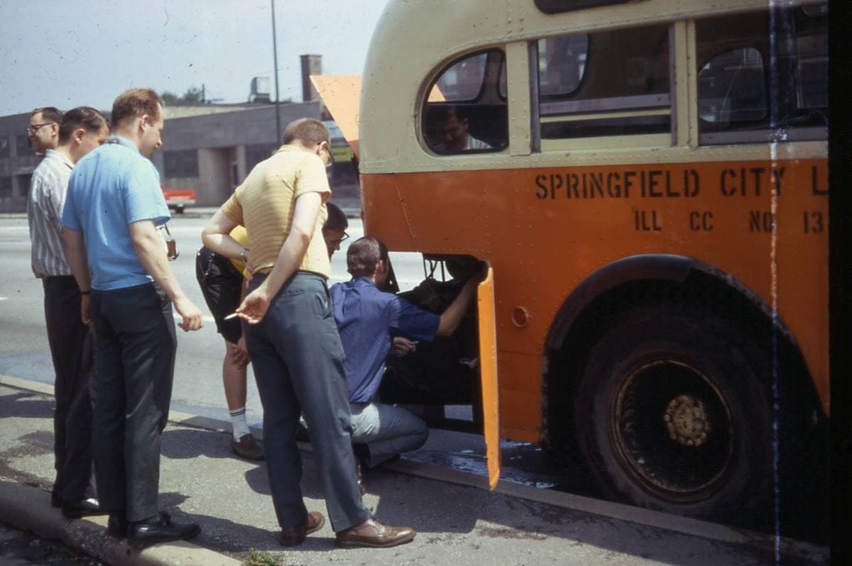 Men looking at an old city bus parked on Ogden Avenue, 1968