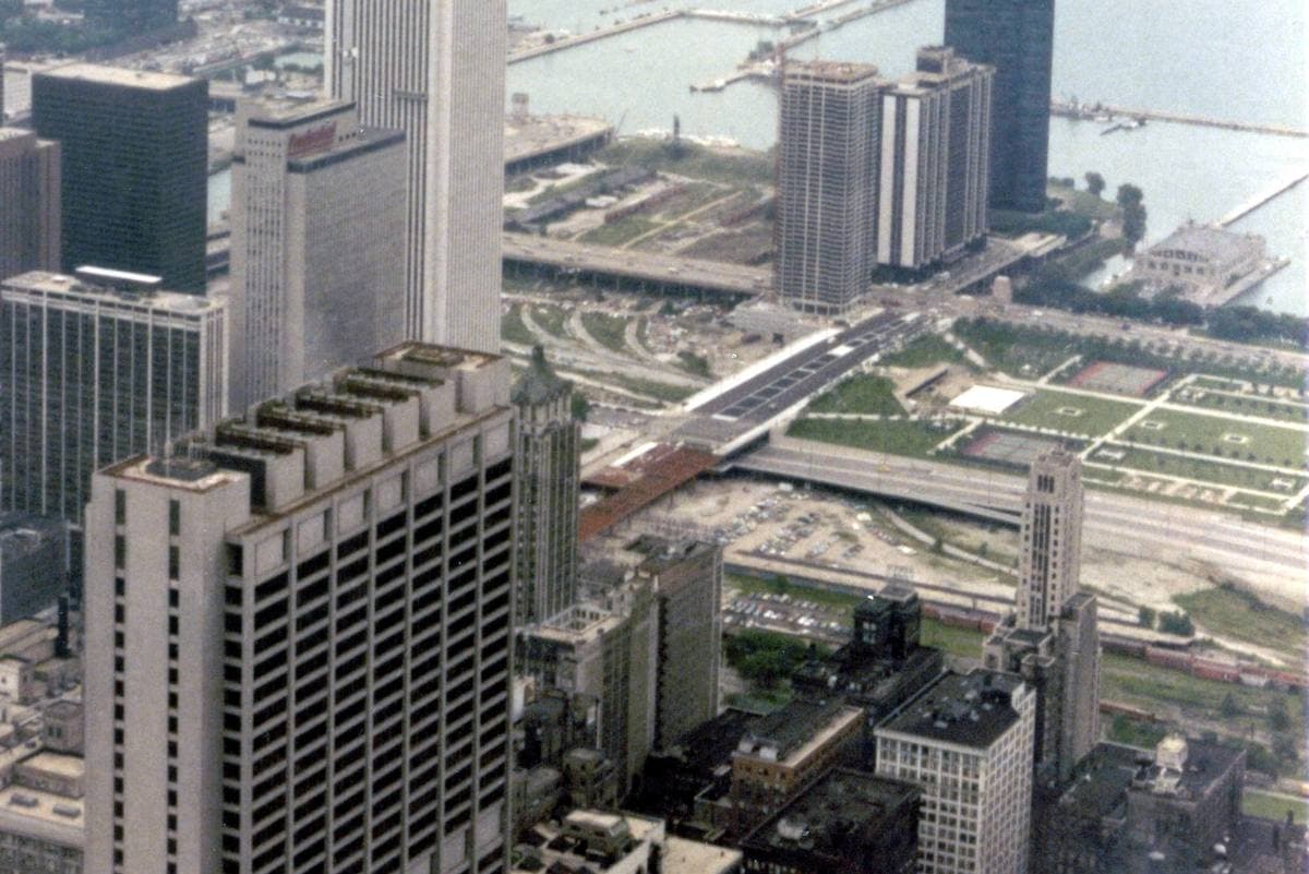 A high view over downtown Chicago towers to Grant Park, rail yards and Lake Michigan
