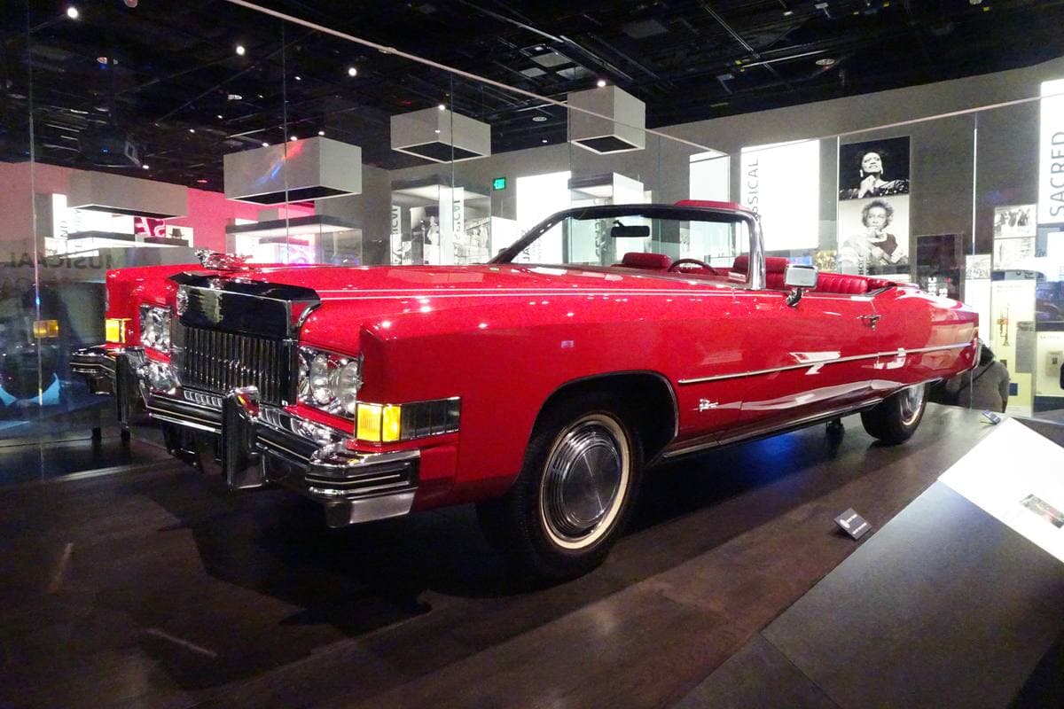 A red Cadillac convertible on display in a museum gallery