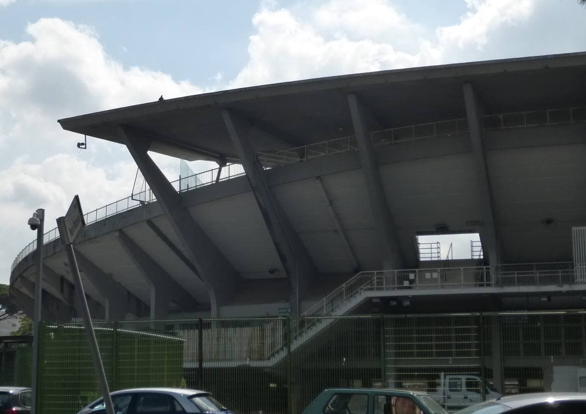 The ribbed concrete canopy of a 1950s stadium stand seen from the street