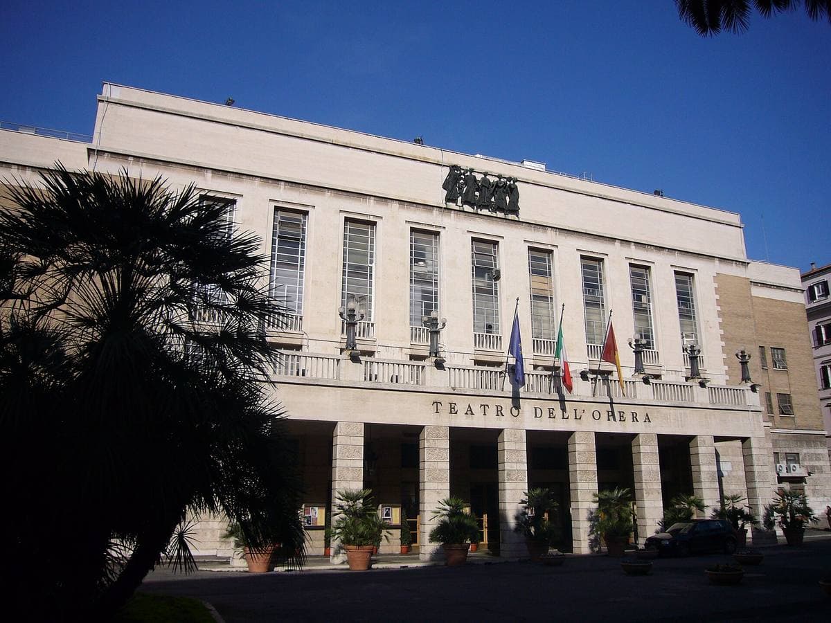 A pale stone theatre front with a long portico on a Rome square