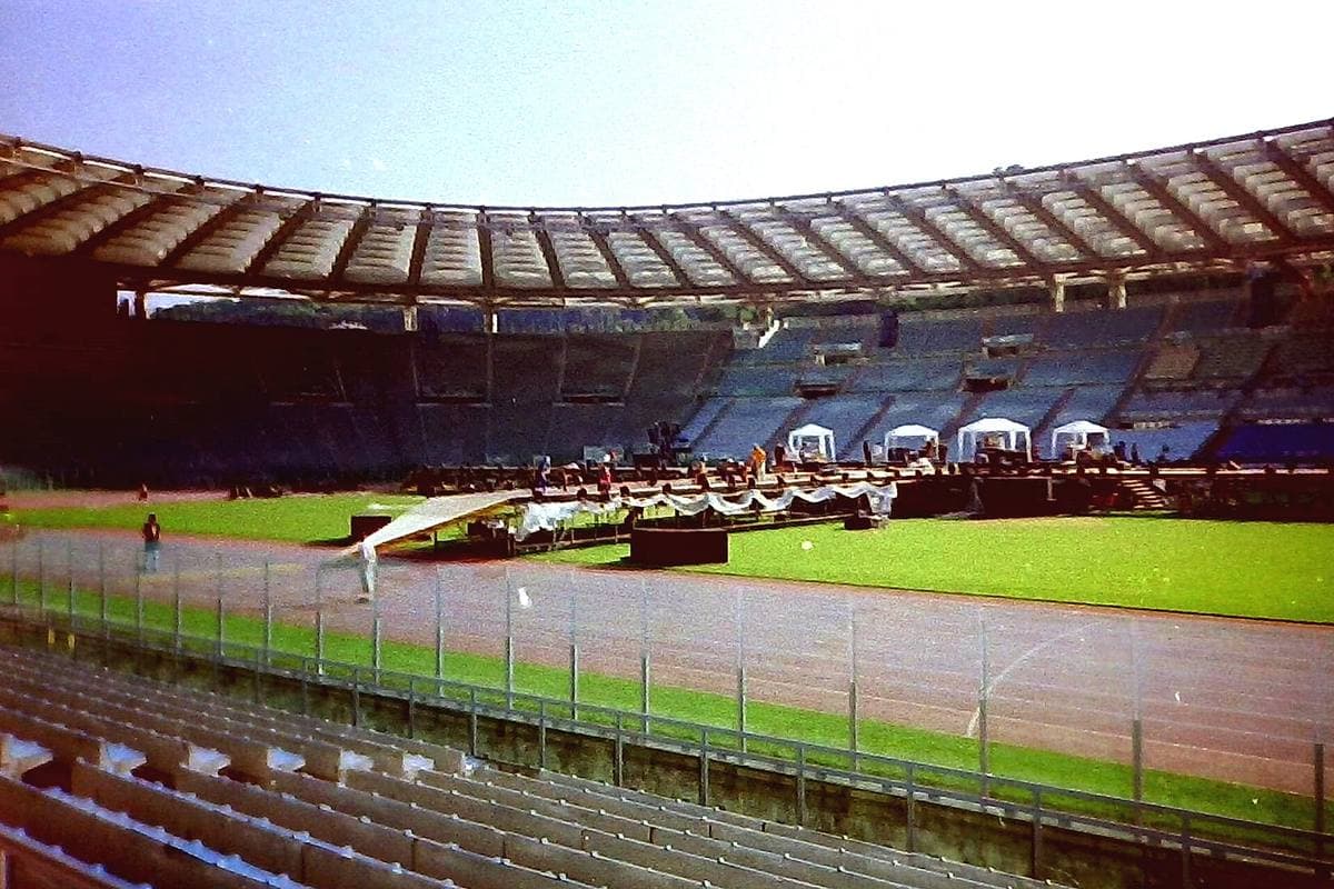 A long stage running across the middle of the Stadio Olimpico pitch, with empty stands behind