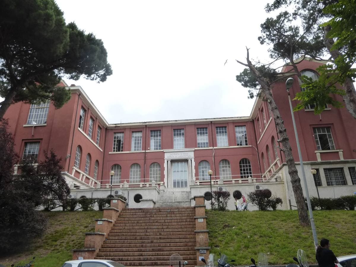 A red-brick faculty building with a central stair and steps rising to its door