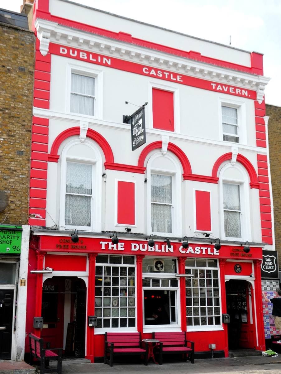 A pub front painted bright red and white with the name across the top