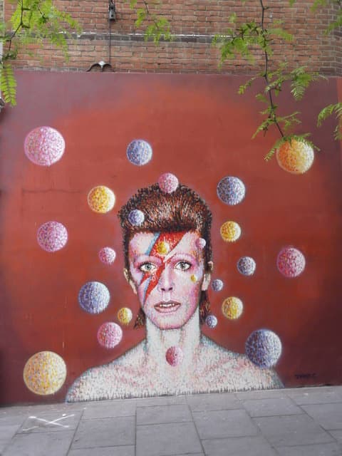 A painted portrait of Bowie with a lightning flash across his face on a shop wall
