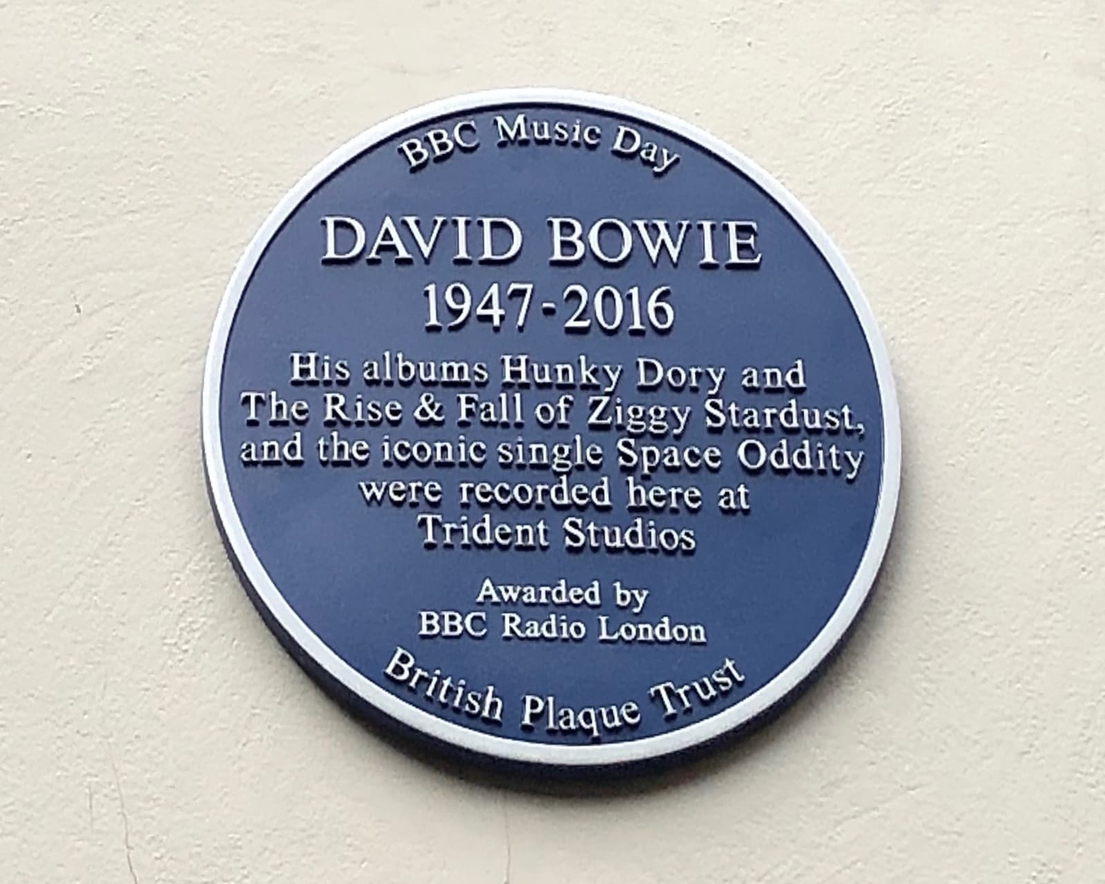 A blue plaque for David Bowie on a brick wall