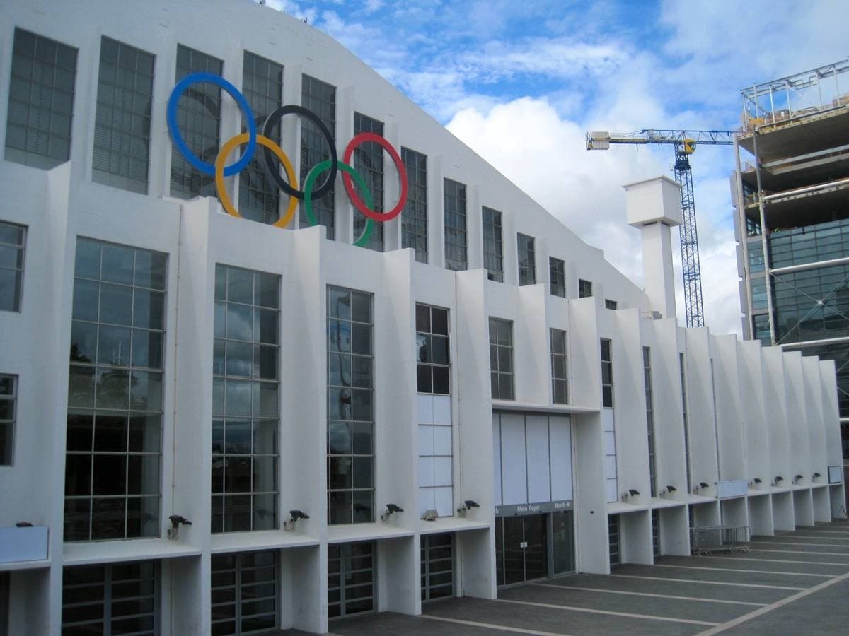 The long white columned front of Wembley Arena with large Olympic rings on the wall