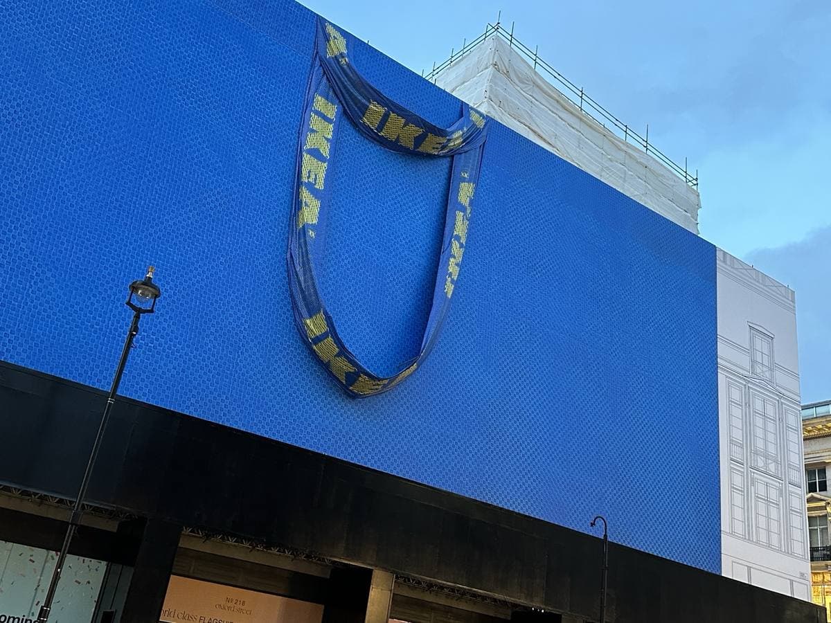 A building front at Oxford Circus covered in a giant blue wrap with a yellow bag handle