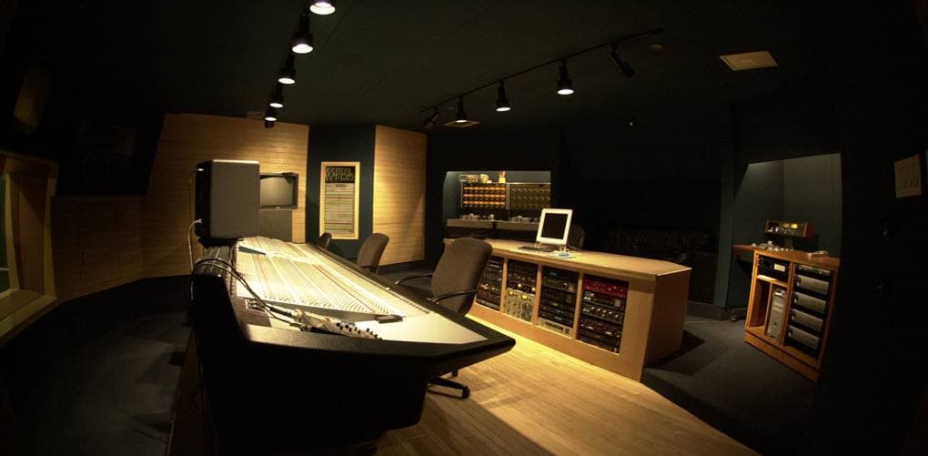 A recording studio control room with a large mixing console