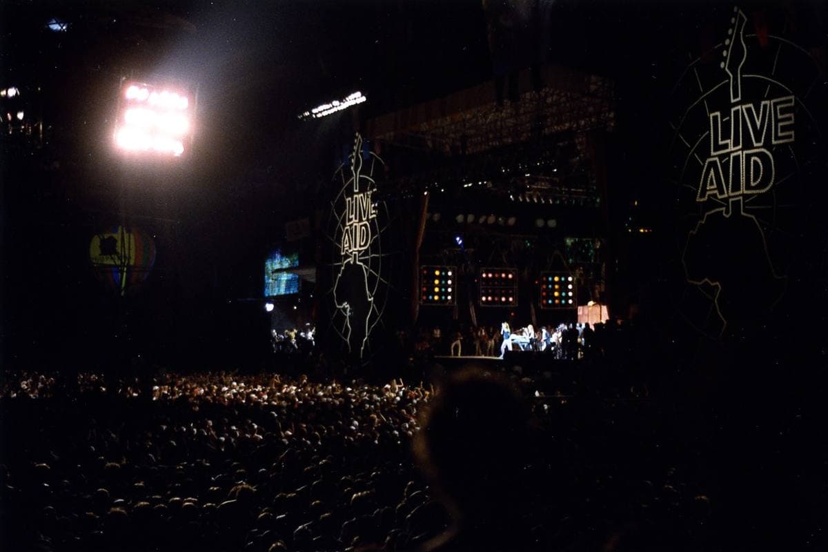 A packed stadium at night facing a lit stage, July 1985