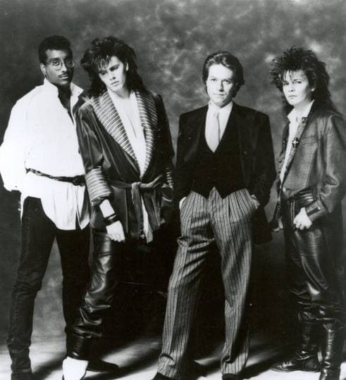 Four men in suits in a 1985 publicity photograph for The Power Station
