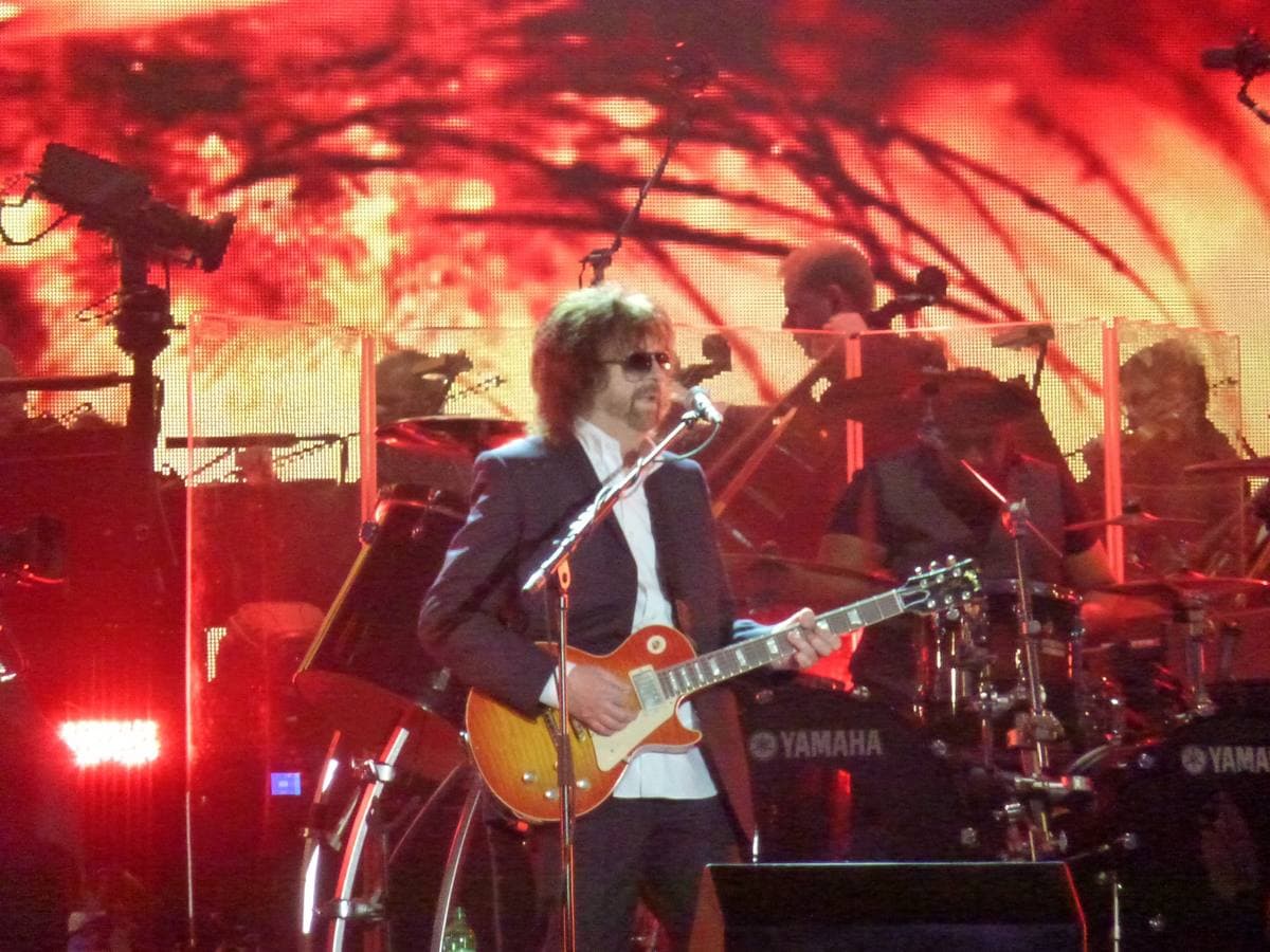 Jeff Lynne in dark glasses singing at a microphone on the Hyde Park stage